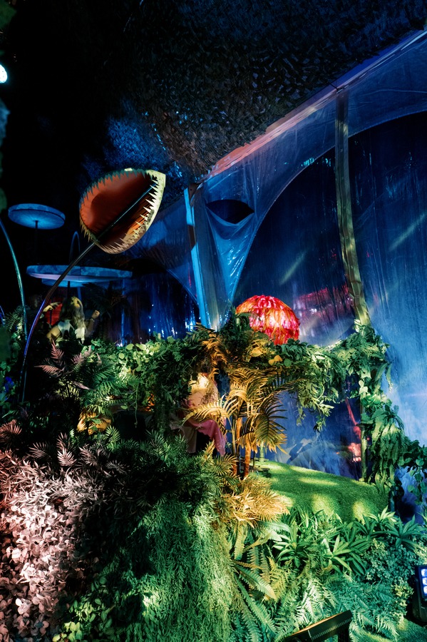 Cenário de selva construído, com uma criatura gigante iluminada a azul e verde, no evento WILD